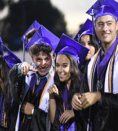 graduates pointing at camera