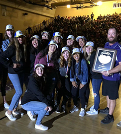 Group of students and a staff member pose with a championship plaque